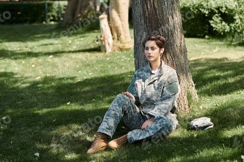 Preview: Homecoming of a young soldier in camouflage uniform sitting by a tree