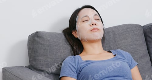 Preview: Woman apply face mask on face and lying on sofa