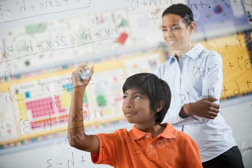 Preview: A student writing formula and equations on a clear perspex board, with pens.