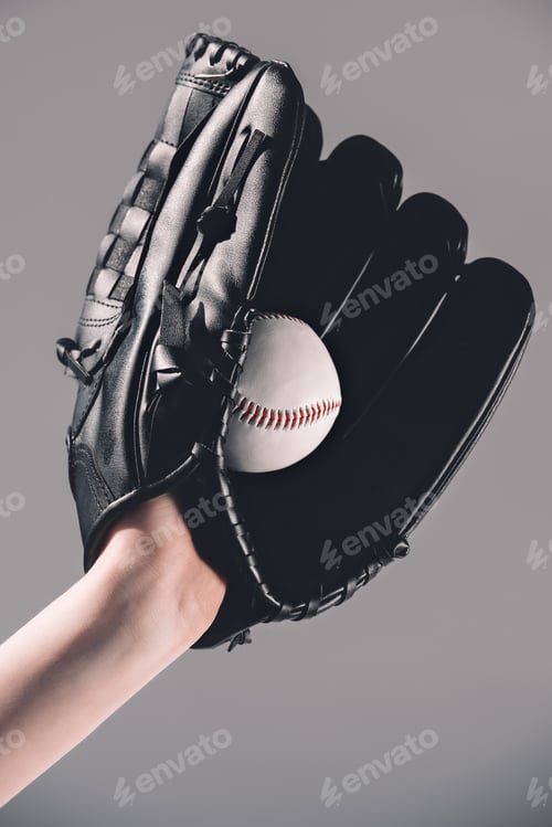 Preview: Close-up partial view of woman in baseball glove holding ball on grey