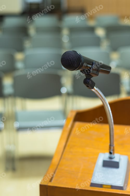 Preview: Microphone on the speech podium over the Abstract blurred photo of conference hall