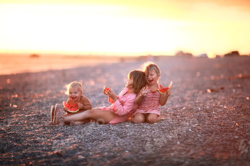 Preview: happy kids with a watermelon at sunset on seashore, summer happy childhood