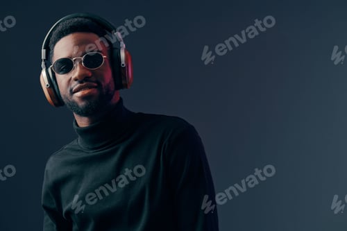 Preview: Stylish young black man in headphones exuding confidence and coolness, wearing a black turtleneck