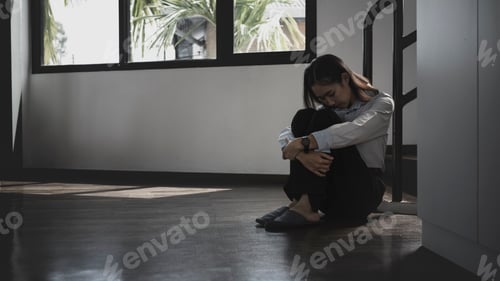 Preview: Lonely young woman sitting on the floor in a dark room with feeling sad and depressed.