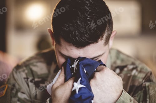 Preview: American soldier mourning and praying with the American flag in his hands