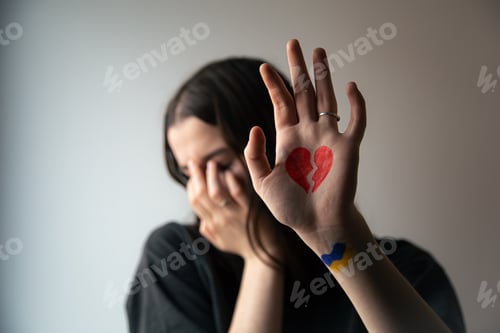 Vorschau: Ukrainisches Mädchen mit gebrochenem Herzen auf der Hand, Schmerz für die Ukraine.