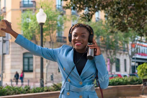 Visualização: Mulher negra está ouvindo música com fones de ouvido em um parque de uma cidade