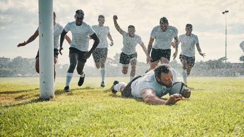 Preview: Full length shot of a handsome young rugby player scoring a try while training on a rainy day