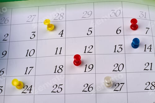 Preview: Many colorful push pins on a monthly paper calendar page.