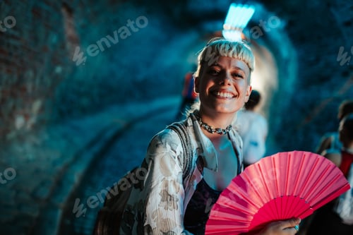 Preview: Young woman smiling and holding a pink folding fan at a festival