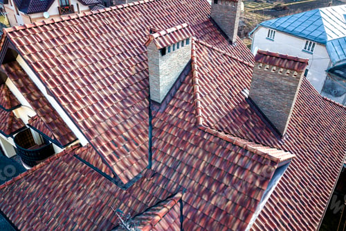 Preview: Aerial top view of complex house metal shingle roof and high brick chimneys.