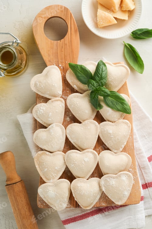 Preview: Italian ravioli pasta in heart shape. Tasty raw ravioli with flour and basil on white background. Fo