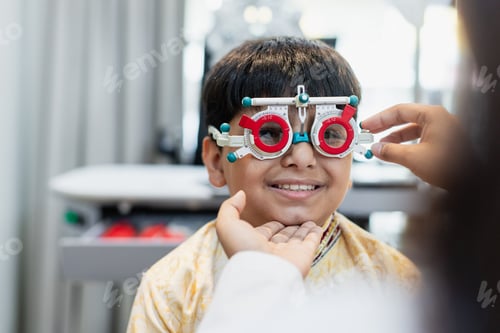 Preview: Happy Indian child boy with women eye specialist examining eyesight modern