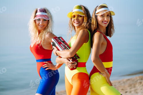 Preview: Dancing on beach. Woman in colorful swimsuits are dancing in morning. ?oncept of fitness, aerobics.