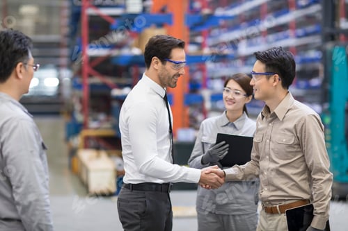 Preview: Businessman and engineer shaking hands in the factory