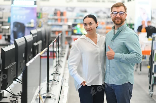 Preview: Young couple shopping at tech store. Buying new tv set for their home