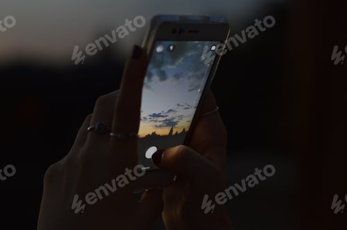 Preview: Closeup shot of a person taking a photo of the beautiful sunset with a smartphone