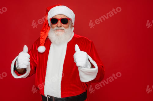 Preview: Happy Santa Claus showing thumbs up hands likes gesture standing red background space