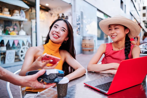 Preview: two asian women pays the bill using a credit card