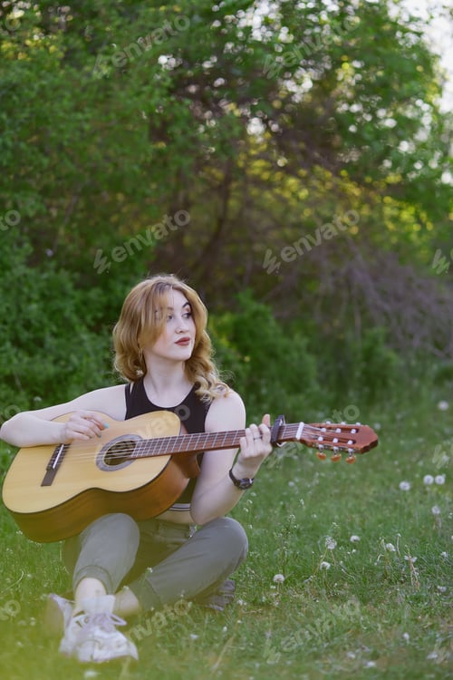 Preview: Beautiful girl playing guitar in spring sunny weather. Closeness to nature, self-discovery concept.