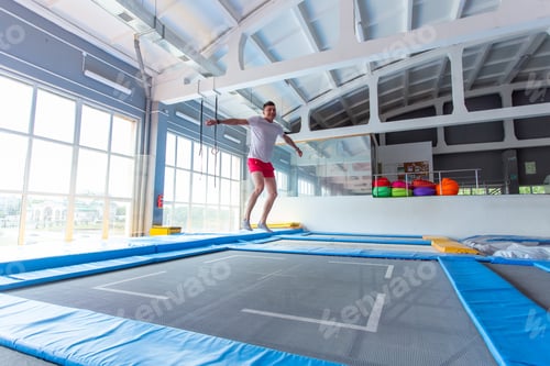 Preview: Fitness, fun, leisure and sport activity concept - Handsome happy man jumping on a trampoline