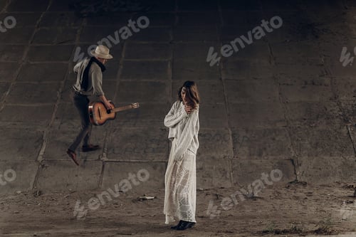 Preview: Indie girl in hipster boho clothes posing in front of handsome cowboy guitar player