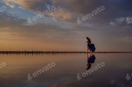 Preview: Elegant woman in silky dress walking by a salt lake.