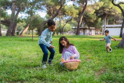 Preview: Children celebrating easter with egg hunt in park