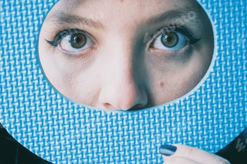 Preview: Close up of young woman's eyes and her face covered by a blue circle