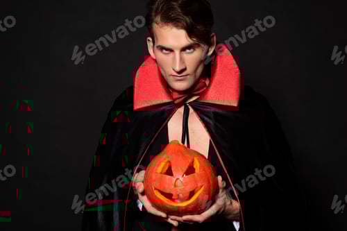 Preview: handsome man holding halloween pumpkin isolated on black