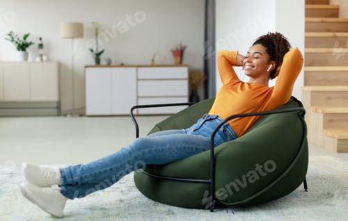 Preview: Calm black woman having rest at home on bean bag
