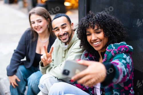 Preview: Group of happy friends taking a selfie outdoors while smiling and gesturing