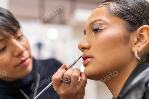 Preview: Professional make up artist applying lipstick on client lips in beauty salon