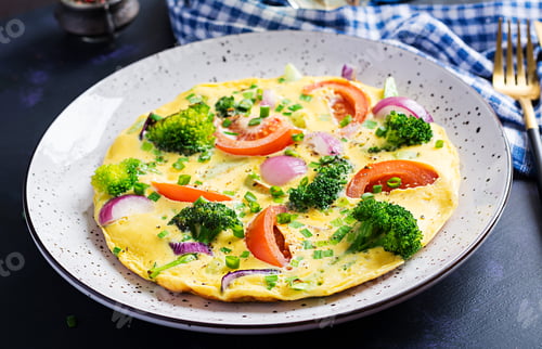 Preview: Omelette with broccoli, tomatoes and red onions on dark table. Italian frittata with vegetables.