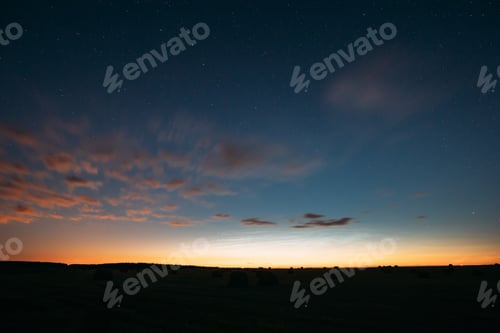 Preview: Night Starry Sky With Glowing Stars Above Countryside Landscape. Light Cloudiness Overcast Above