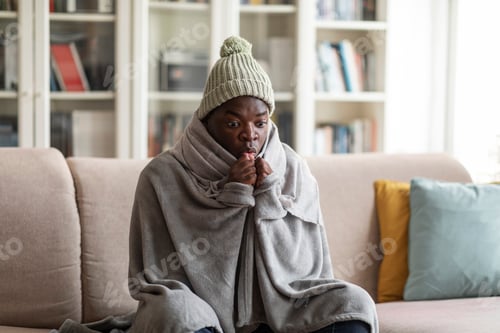 Preview: Man covered in blanket sitting on sofa and warming hands