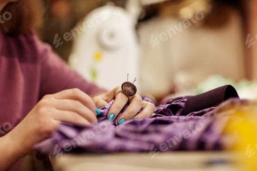 Preview: Female hands sewing cloth with needle at seamstress workplace.