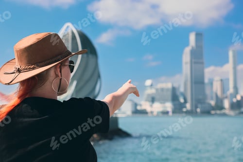Preview: A girl wearing a hat points towards the skyline of Hong Kong\'s harbor on a clear day