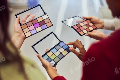 Preview: Women holding bright spring-summer colors palette of eye shadows, indoors.