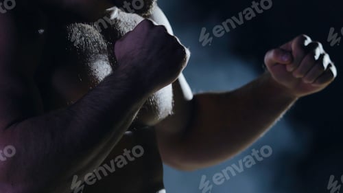 Preview: Boxing man ready to fight. Boxer with strong hands and clenched fists on a black background. Close