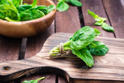 Preview: A bunch of fresh baby spinach leaves on a cutting board and spinach leaves in a bowl
