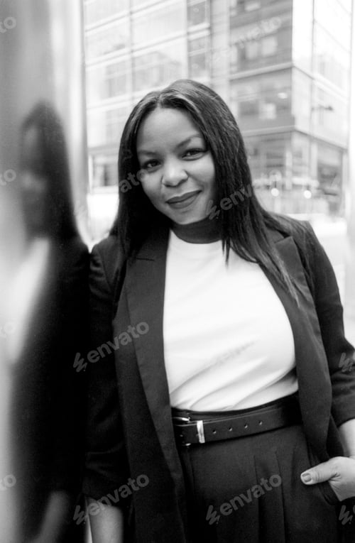 Preview: Smiling businesswoman leaning against modern building in monochrome
