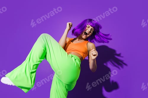 Preview: Carefree woman dancer wearing colorful sportswear having fun against purple background