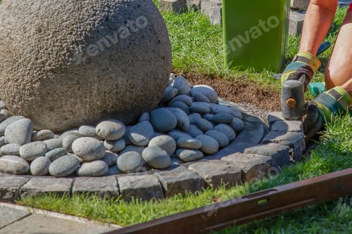 Preview: Closeup shot of a handyman laying cobblestones using a mallet
