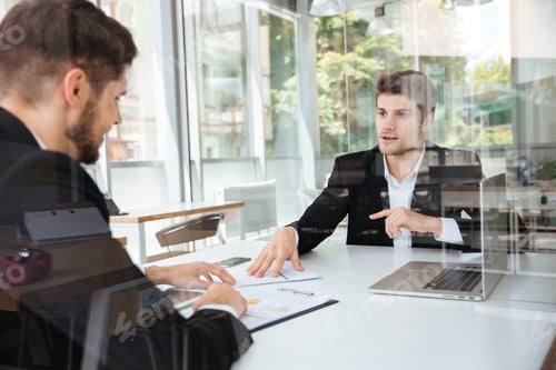 Preview: Two happy businessmen discussing business plan on meeting in office