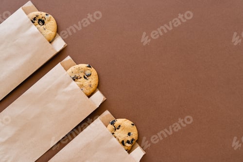 Preview: Top view of cookies in craft packages on brown background with copy space