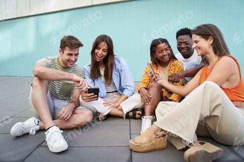 Preview: Group of students using mobiles app outdoors and smiling sitting in a floor checking cell phone