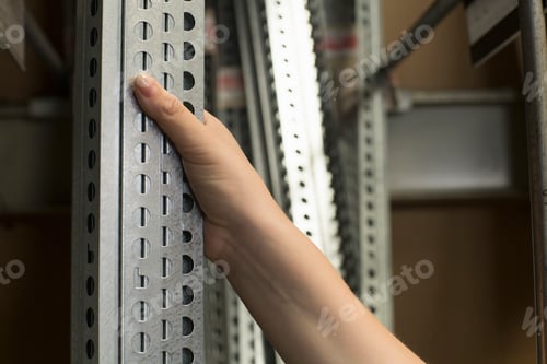 Preview: Hand of female customer selecting metal bars in hardware store
