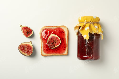 Preview: Figs, jar of jam and piece of bread on white background, top view