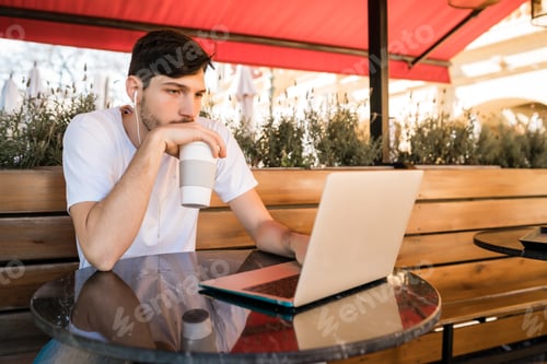 Preview: Young man using his laptop in a coffee shop.